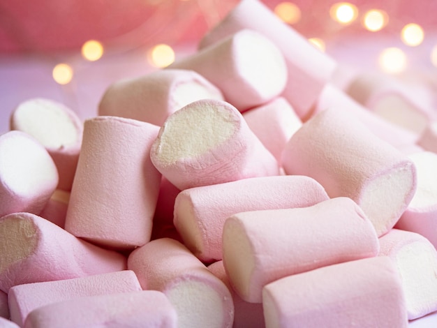 A closeup photo of a tasty pinkwhite marshmallow with lights on a background