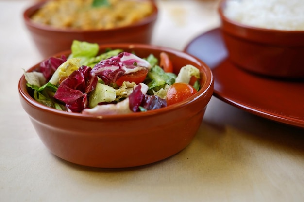 Closeup photo of vegetable salat in bowl with traditional indian dishes at background.