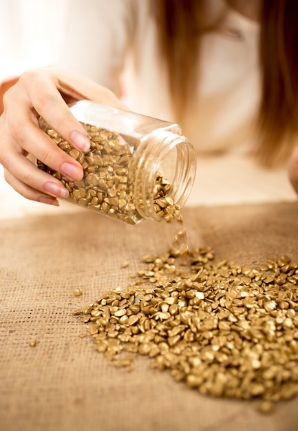 Closeup photo of woman emptying bullion with gold on burlap