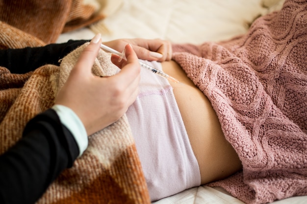 Primo piano di una donna che fa un'iniezione nel sedere di un bambino malato