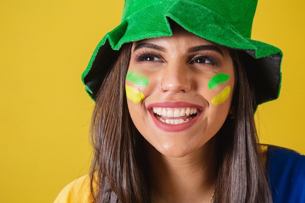 Closeup photo woman supporter of brazil world cup 2022 focus on the look on the smile wearing cheerleading outfit flag and hat