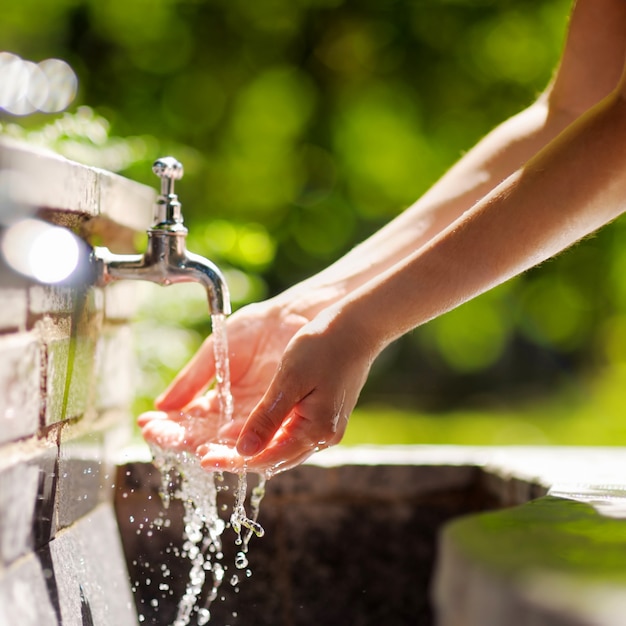 Photo closeup photo of woman washing hands in a city fountain