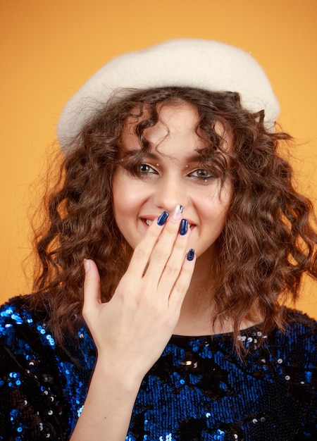 Closeup photo of young curlyhaired girl laughing and putting her hand to her mouth High quality photo