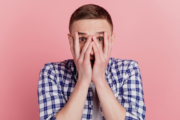 Closeup photo of young guy with open mouth holding arms on face shocked surprised fail problem isolated pink color background