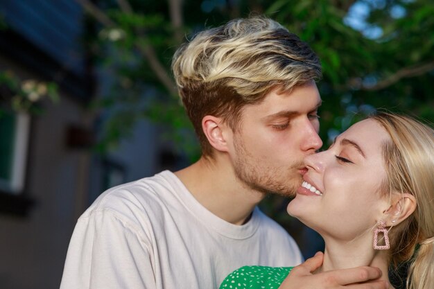 Closeup photo of young man kissing his girlfriend