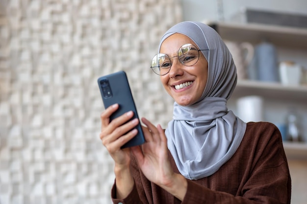 Photo closeup photo young muslim student woman in black hijab sitting at home and using mobile phone