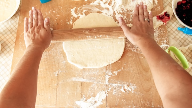 Primo piano della giovane donna che fa l'impasto per la pizza