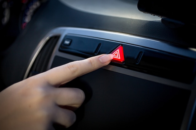 Closeup photo of young woman pressing emergency button in car