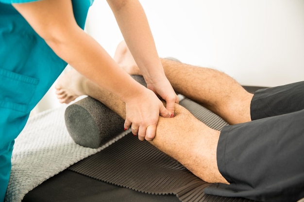 Closeup of physiotherapist hands massaging calf muscle of patient in hospital