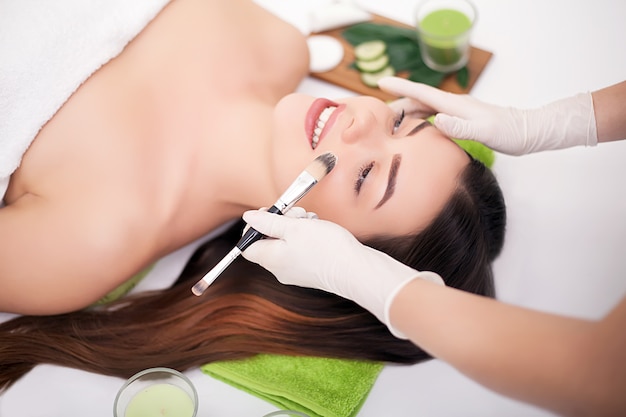 Closeup picture of lovely young woman with cream mask in a beauty parlour.