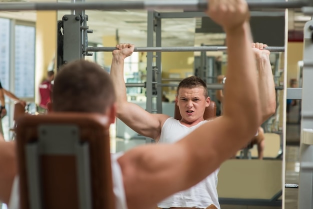 Closeup picture of sportsman Guy pushing barbell in gym Man concentrated on sport