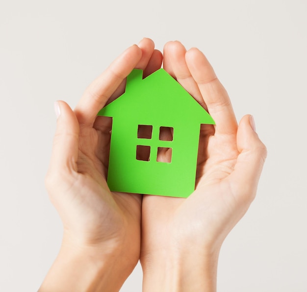 closeup picture of woman hands holding green house