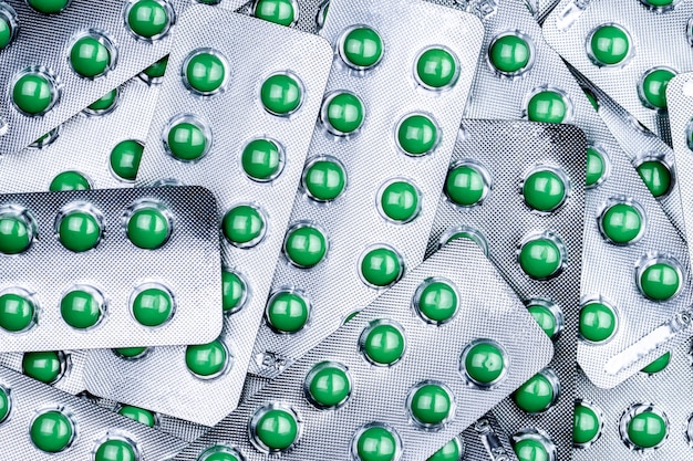 Closeup pile of round green sugar coated tablet pill in blister pack. Combine pill for relief cough. Pharmaceutical product. Pharmaceutical industry. Pharmacy background. Medicine for dry cough.