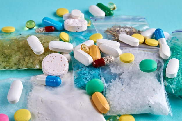 Closeup pile of various colorful pills with capsules and tablets medicine vitamins on blue backgroun