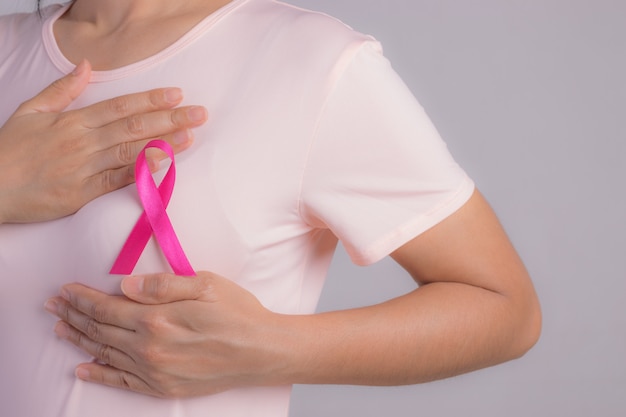 Closeup of pink badge ribbon on woman chest to support breast cancer cause