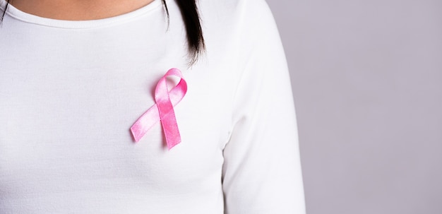 Primo piano del nastro distintivo rosa sul petto della donna per sostenere la causa del cancro al seno