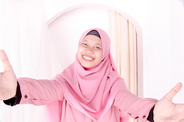 крупный план женщины в розовом хиджабе обеими руками, желая обнять, вид спереди