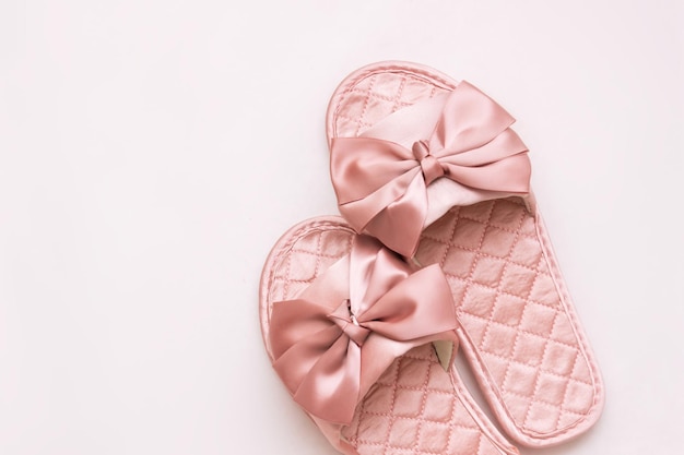 Closeup of pink satin female glamorous home slippers with bows isolated on a white background