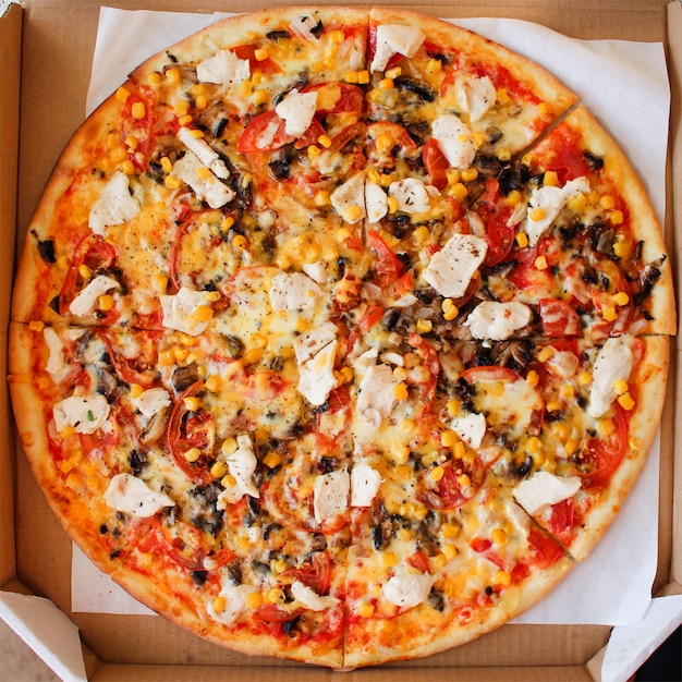 チキン、トマト、コーン、チーズ、マッシュルーム、スパイスのピザのクローズアップ。上面図。