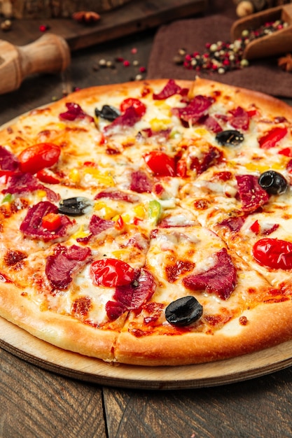 Крупным планом на пиццу с копченой говядиной и овощами на деревянном столе