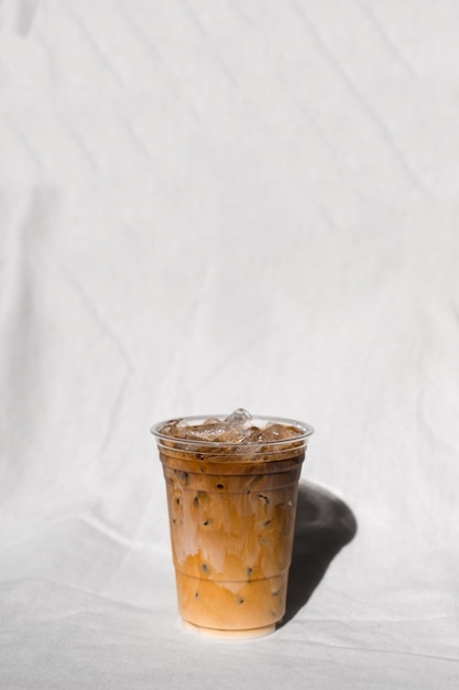 Фото Крупным планом пластиковый стаканчик кофе со льдом с молоком на столе