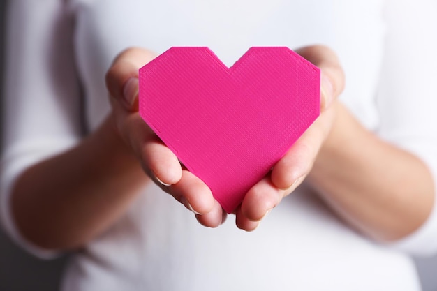 Closeup of plastic puzzle heart in female hands