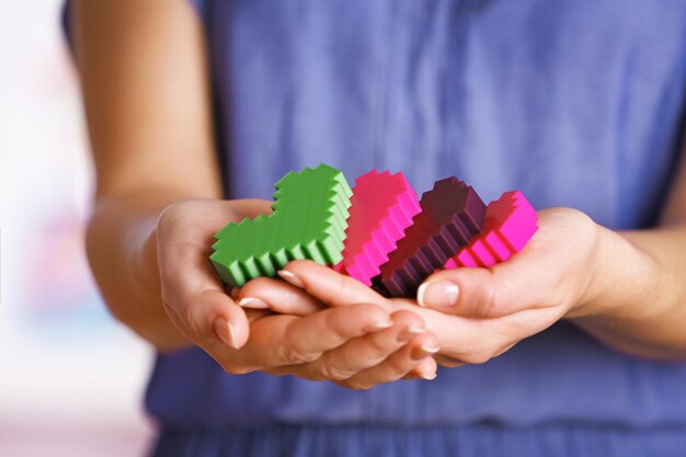 Closeup of plastic puzzle hearts in female hands