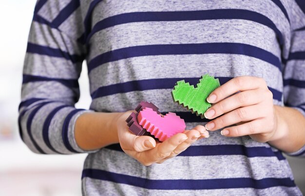 Closeup of plastic puzzle hearts in female hands