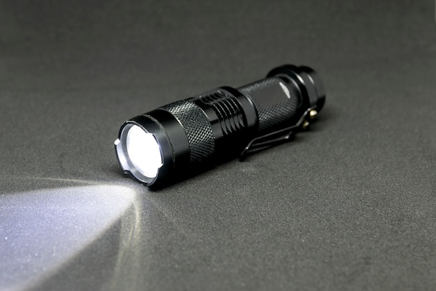 Closeup pocket LED flashlight on dark background.