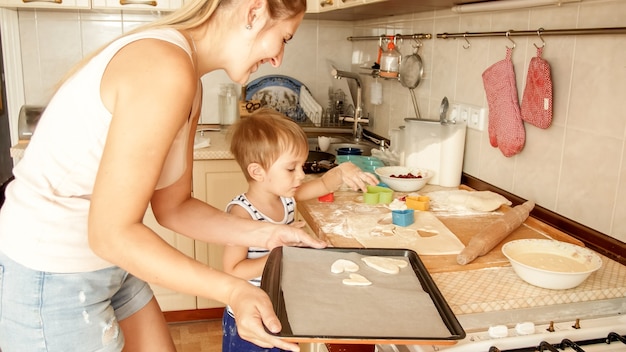 Closeup portrait of adorable 3 years old toddler boy making cookies with mother