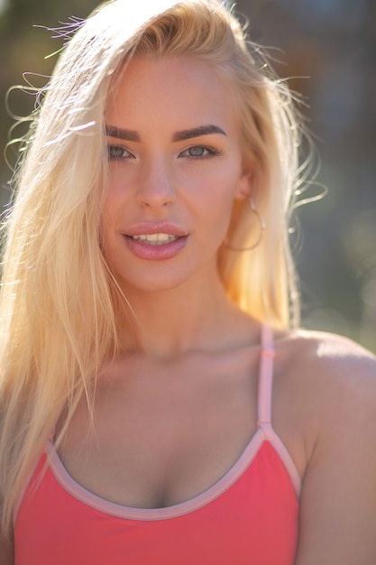 Closeup portrait of an adorable woman with long hair wears sport bra posing in sunny day