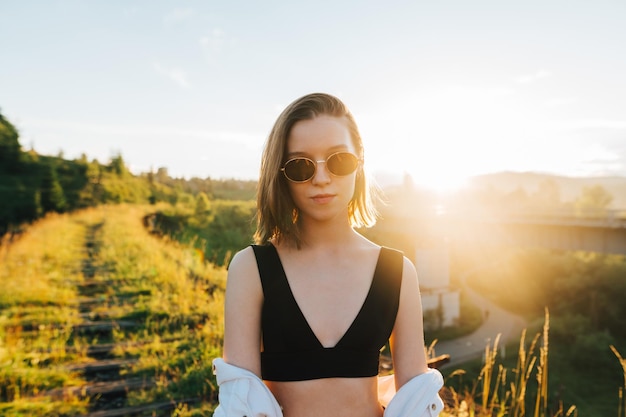 Closeup portrait of an attractive lady in sunglasses standing on a guess and posing at the camera