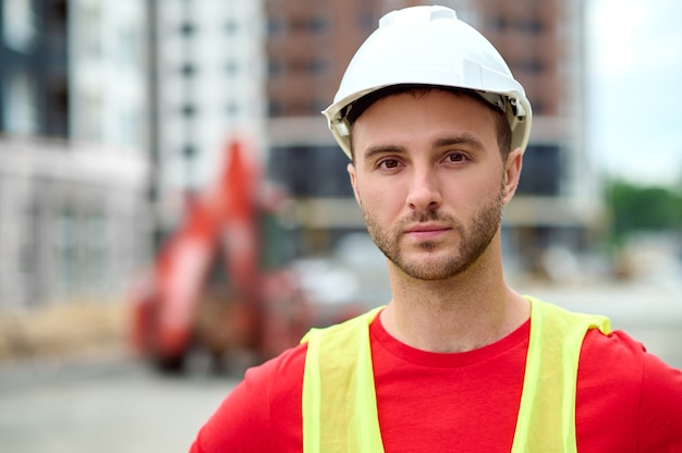 Closeup portrait of an attractive male builder in a hardhat and a reflective waistcoat looking ahead