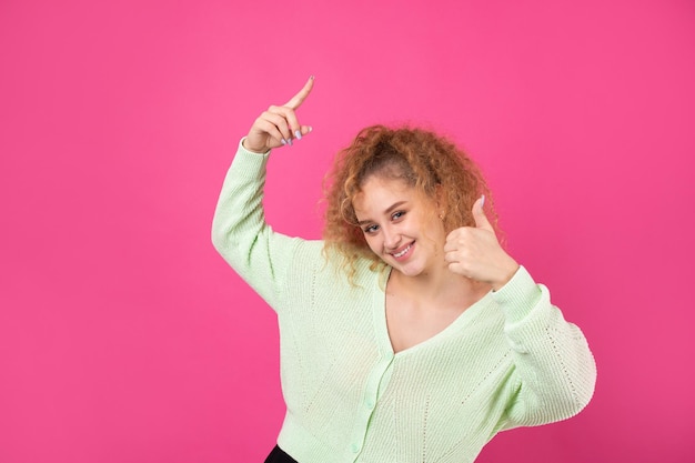 Closeup portrait of attractive surprised girl showing thumbs up gesture Success luck concept