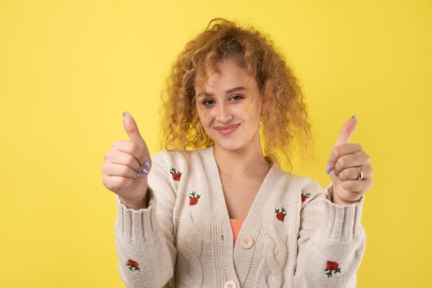 Closeup portrait of attractive surprised girl showing thumbs up gesture Success luck concept