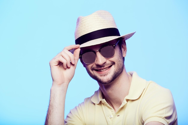 Closeup portrait of awesome hipster wearing fedora hat with intense look at camera Headshot over blue studio background