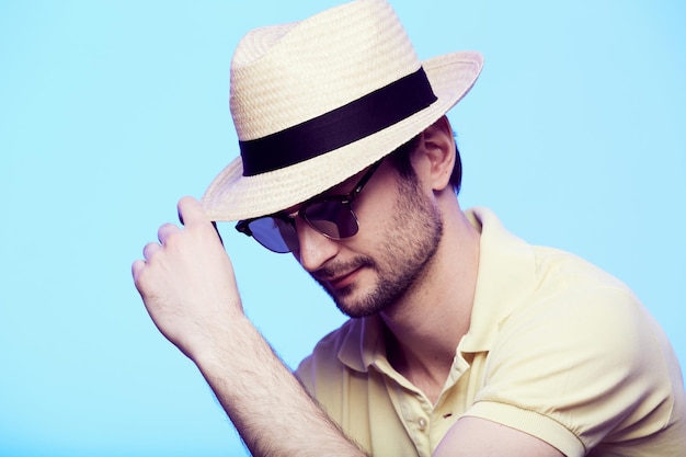 Closeup portrait of awesome hipster wearing fedora hat with intense look at camera Headshot over blue studio background