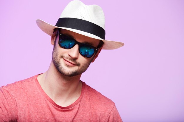 Closeup portrait of awesome hipster wearing fedora hat with intense look at camera Headshot over pink studio background