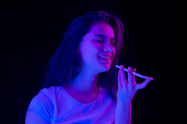 Closeup portrait of beautiful girl over dark background in neon light