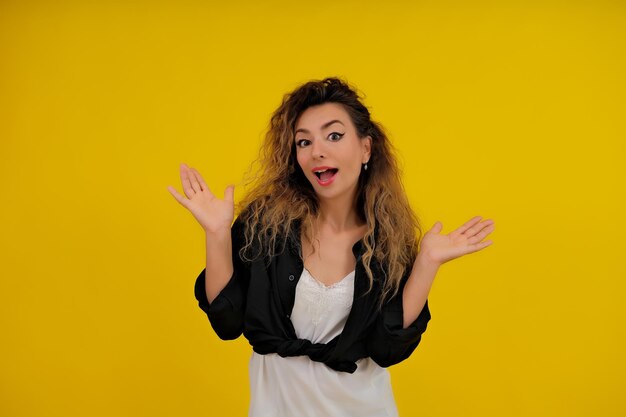 Closeup portrait of a beautiful girl on a yellow background woman shows surprise shocked surprised stunned positive human emotions