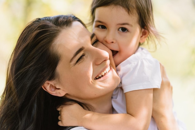 Closeup portrait of beautiful portrait of happy smiling mother and her little cute girl kid play outdoors Good relationship of happy family Happy Mothers Day Motherhood and childhood concept