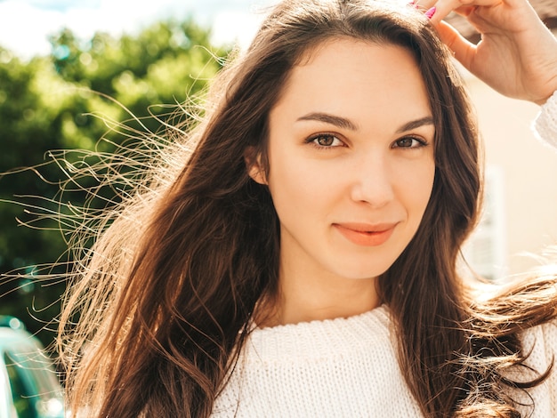 Closeup portrait of beautiful smiling brunette model. Trendy girl posing in the street 