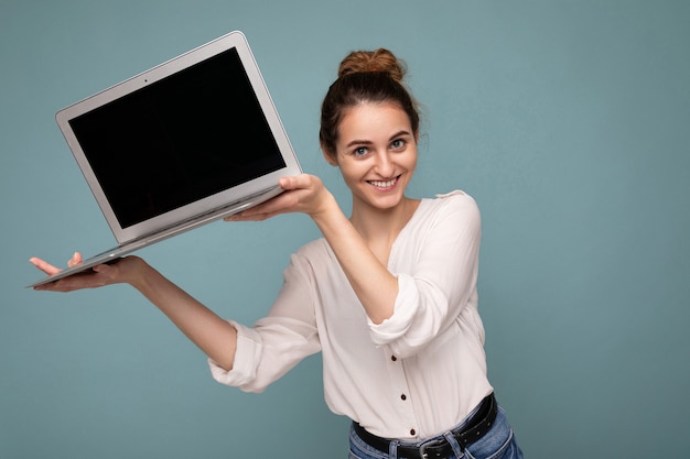 Foto ritratto del primo piano di bella giovane donna sorridente felice che tiene il computer portatile che esamina macchina fotografica