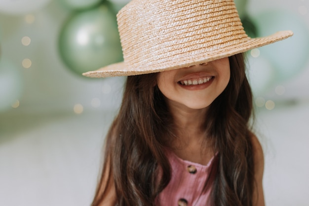 Photo closeup portrait of a beautiful smiling little darkskinned girl with dark hair in a straw hat