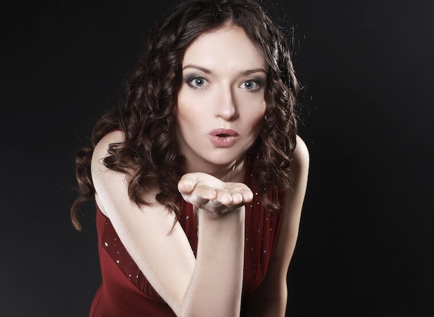 Closeup portrait of beautiful woman in red dress sending a kiss