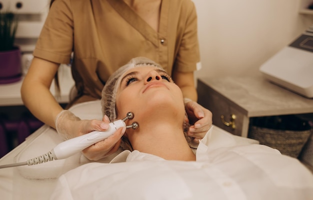 Closeup portrait of a beautiful woman with closed eyes and\
apparatus for skin rejuvenation beauty salon procedures rf lifting\
microcurrents