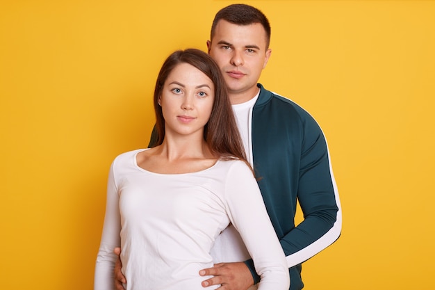 Closeup portrait of beautiful young couple isolated on yellow