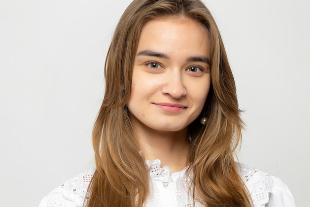 Closeup portrait of a beautiful young girl with dark hair in a studio on a whitegray background