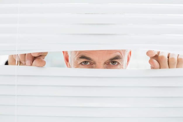 Closeup portrait of a businessman peeking through blinds