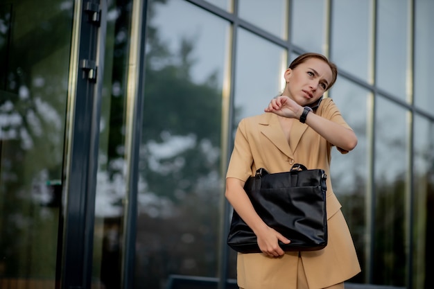 Closeup Portrait of an businesswoman standing outside office building and speaking mobile phone.